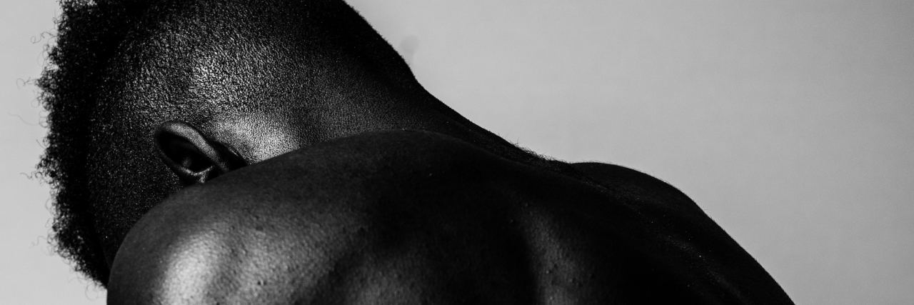 How to Deal With Social Anxiety Caused by Chronic Illness black and white photo of young man holding hands close to body in embrace, facing away from camera