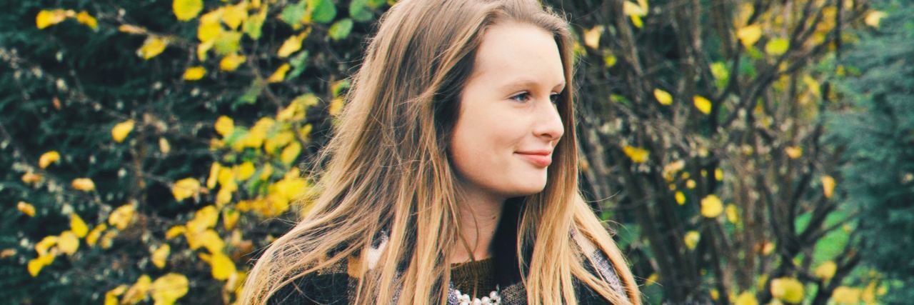 Pretending Your Life Is Perfect but You Want to Die photo of young blonde woman standing in front of autumnal tree and smiling