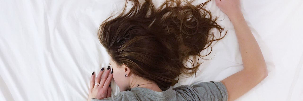 My Mantra for Getting Through a Pain Flare Woman lying in bed with her back to the camera