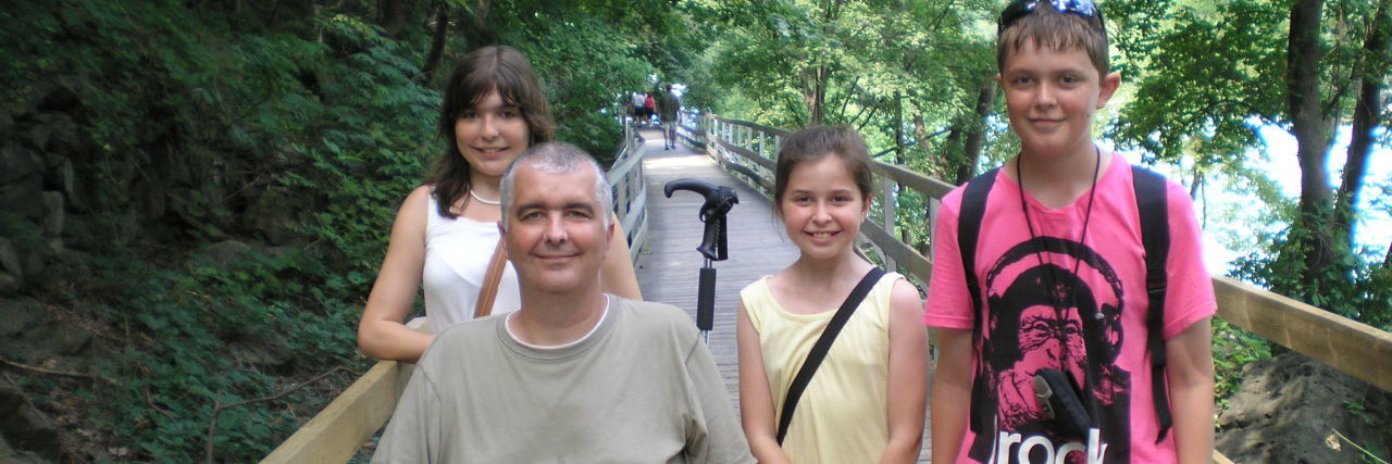 Suzanne's family on a wooden bridge. Her father is sitting in his wheelchair.
