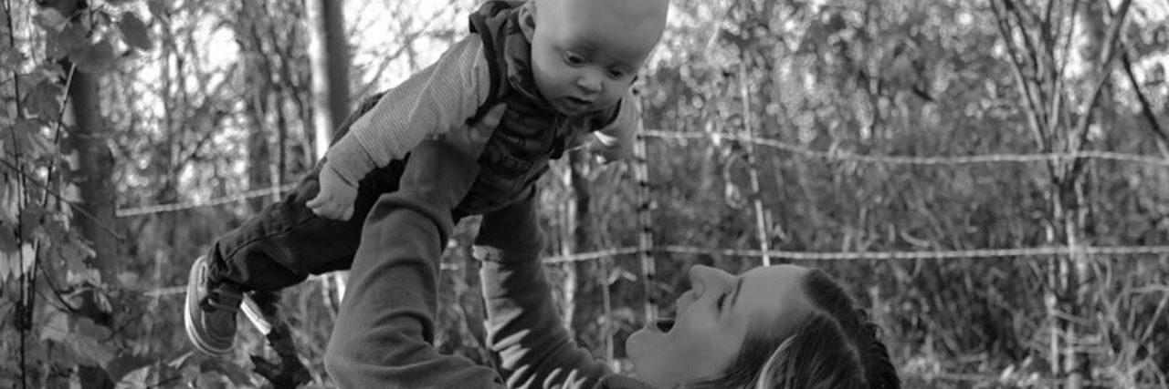 Why Society Should Stop Putting Pressure on Moms to Breastfeed a mother playfully holding her son up in the air