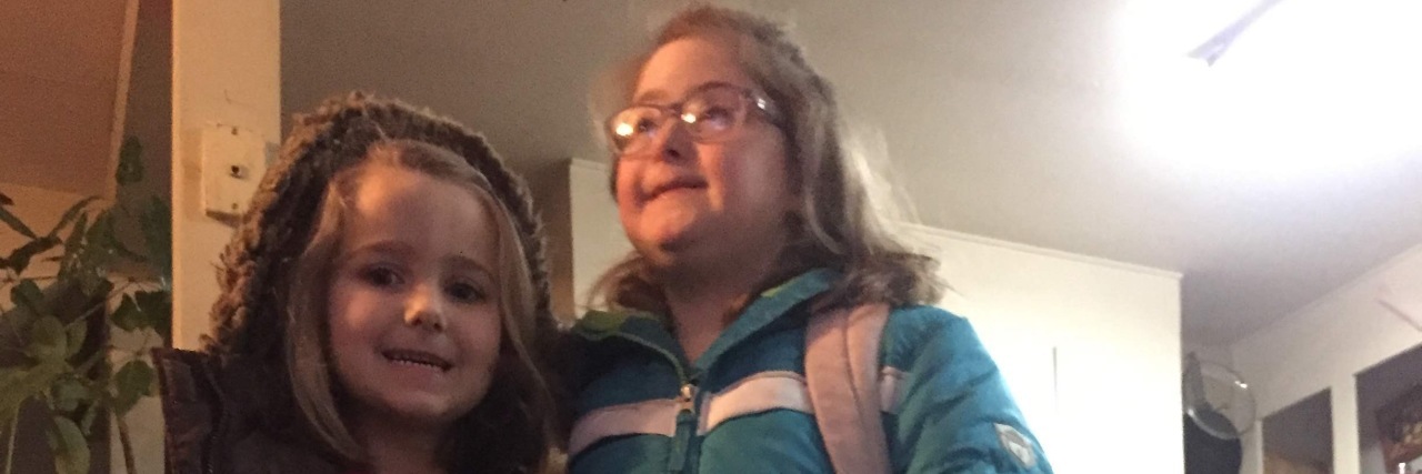 Talking to Kids About Down Syndrome Jenny's daughters, one nrurotypical and one with Down syndrome, dressed for the winter.