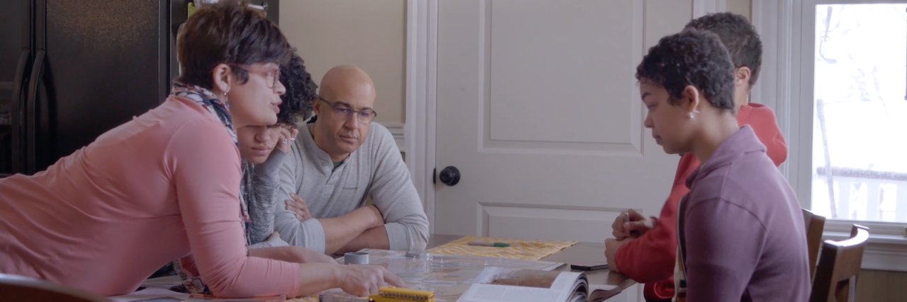 PSA 'A Good Man' Shows Couple's Journey With Early-Onset Alzheimer's craddock family looking at maps and books at dinner table
