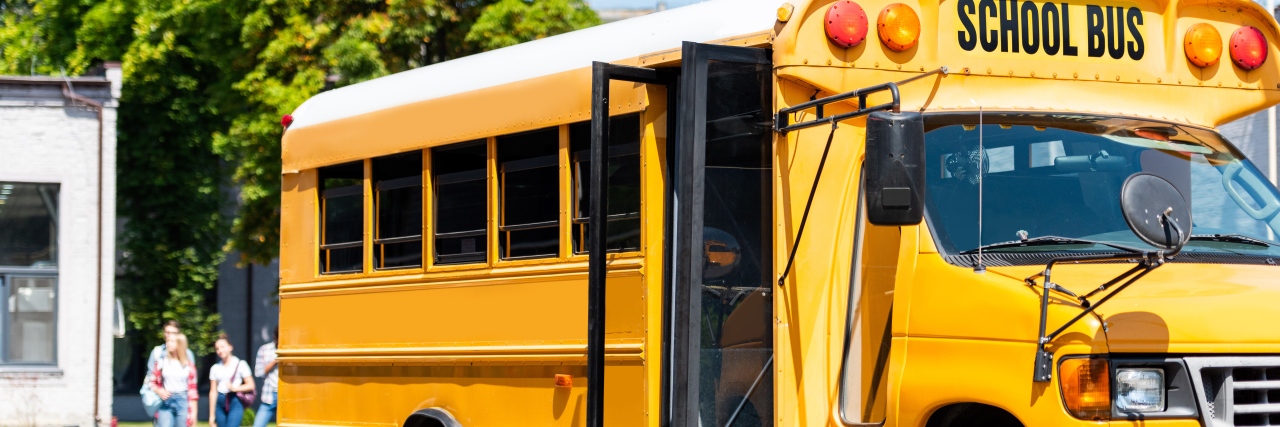 a school bus parked with blurred students walking nearby