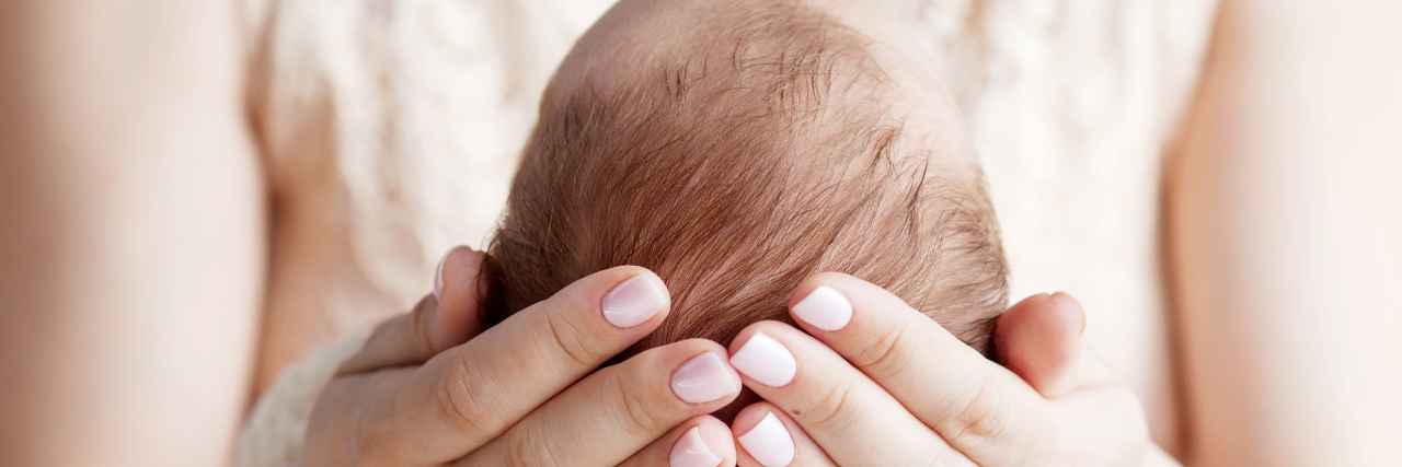 Egg Donor Recipients Who Are Questioned About Being a Real Mom a mother holding the head of her newborn baby