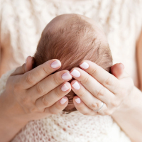 a mother holding the head of her newborn baby