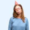 woman wearing birthday hat with sleepy expression