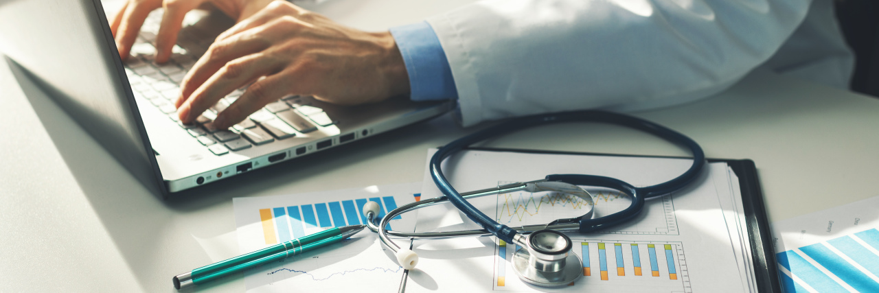 Doctors Must Stop Dismissing Unexplained Chronic Pain Doctor making notes on laptop.