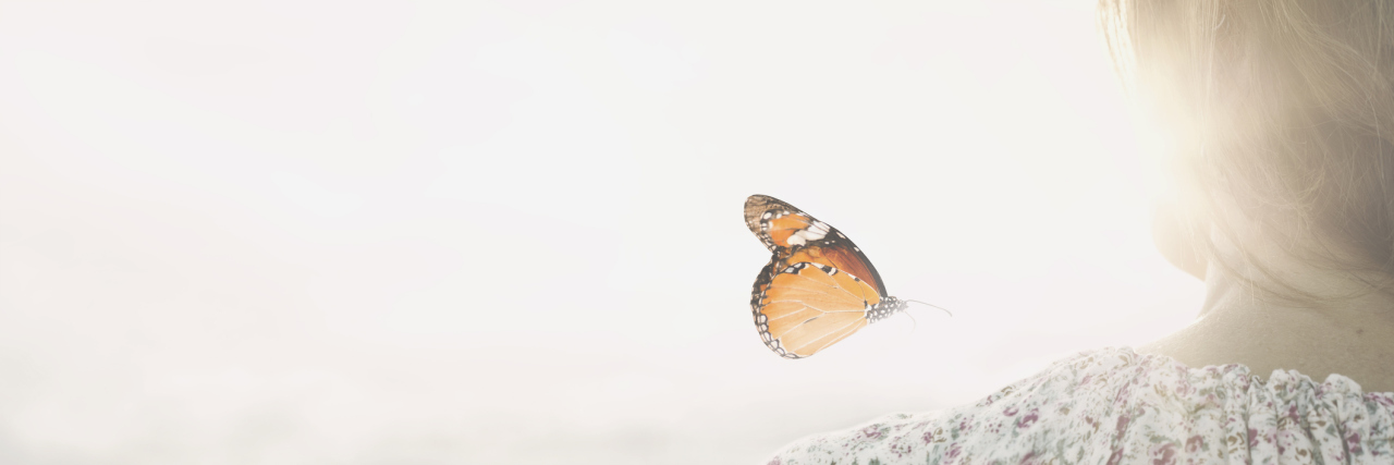 How to Cope With the Grief of Your Child’s Rare Disease Diagnosis a colorful butterfly leans delicately on the shoulders of a woman