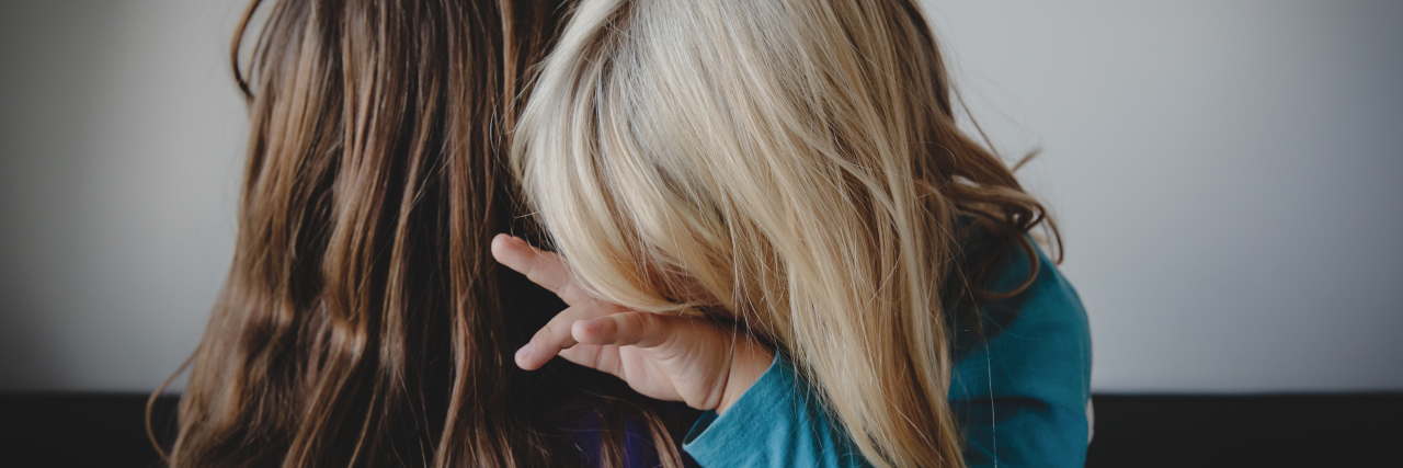 a mother is hugging her sad little girl