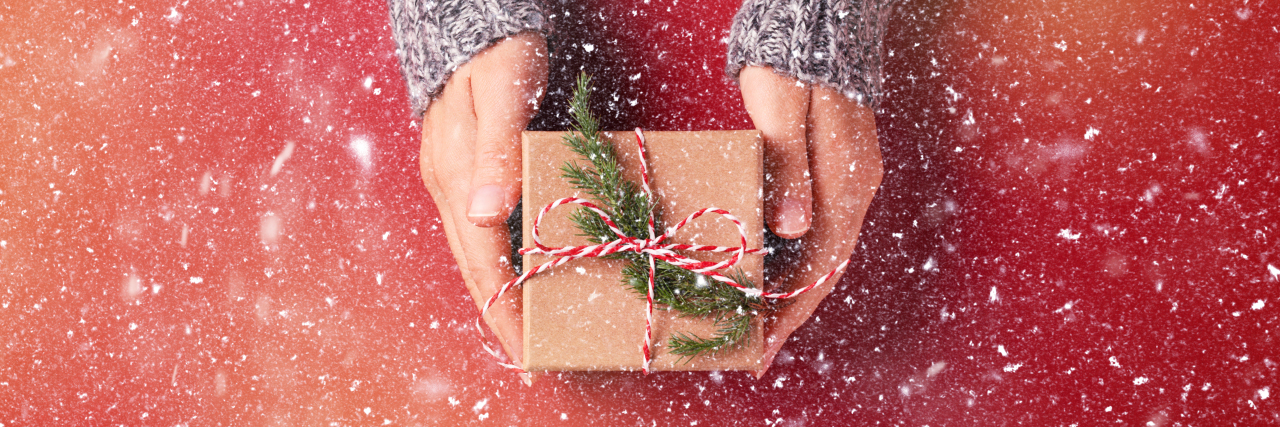 The Gift That Means the Most to Me As a Therapist snowy picture of a woman's hands in a silver sweater giving a brown paper wrapped present