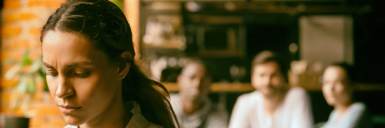 Don't Talk About Me Like I'm Not There Because of My Disability Sad woman with people talking about her behind her back.