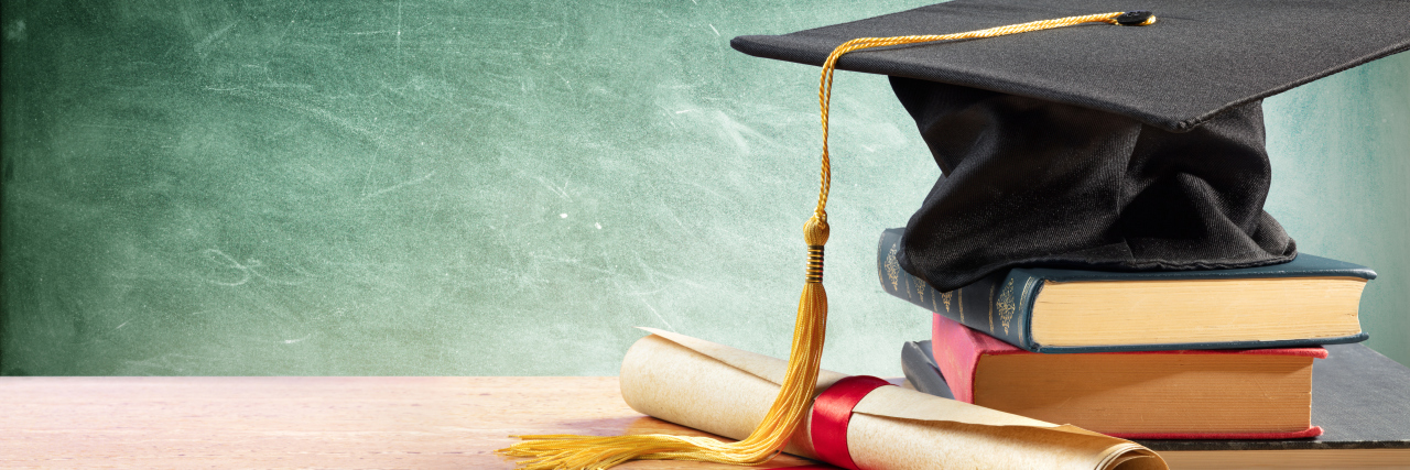 High School Graduation Requirements and Kids With IEPs Graduation cap and diploma on table with books.