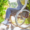 Young woman in a sporty manual wheelchair outside on a sunny day.
