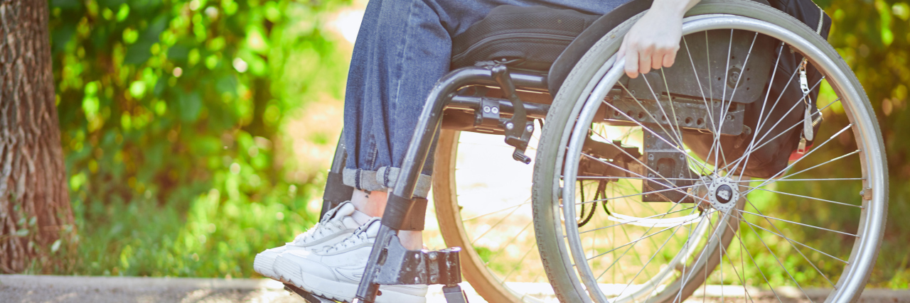 Young woman in a sporty manual wheelchair outside on a sunny day.