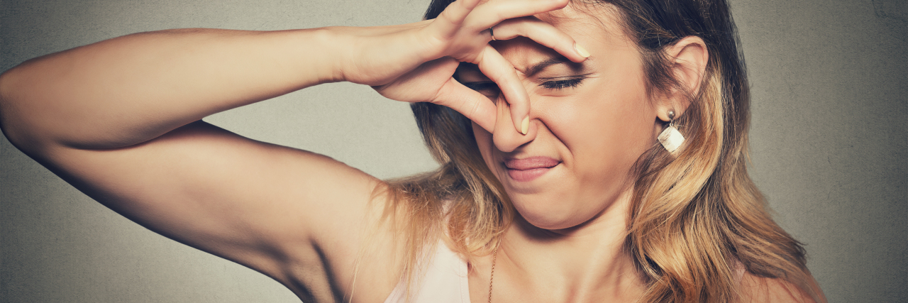 How to Deal With Body Odor From Chronic Illness Woman holding her nose due to bad smell.
