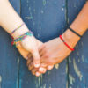 Two friends holding hands in front of a wooden background.