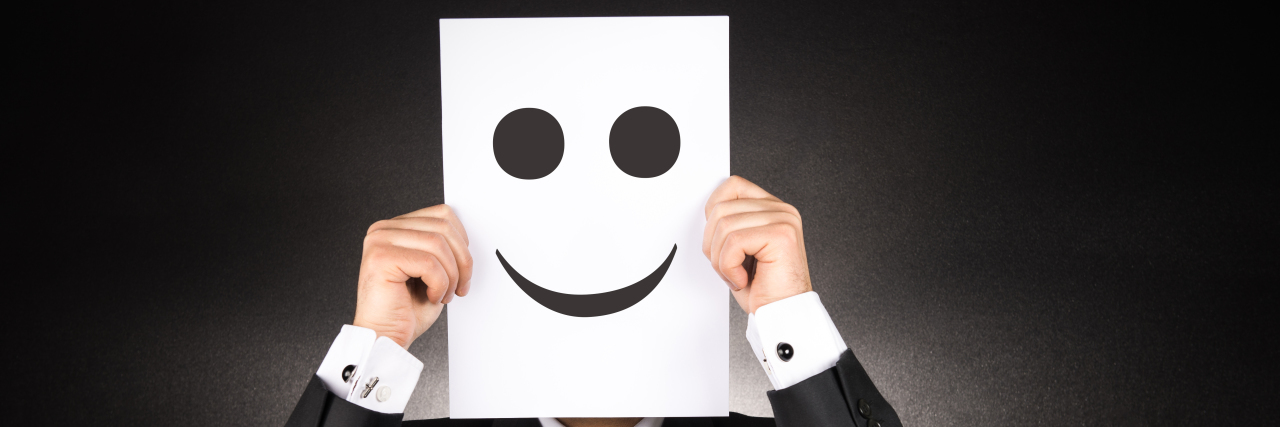 Being Honest About Your Health With Parkinson's Man hiding behind paper cutout of a face.