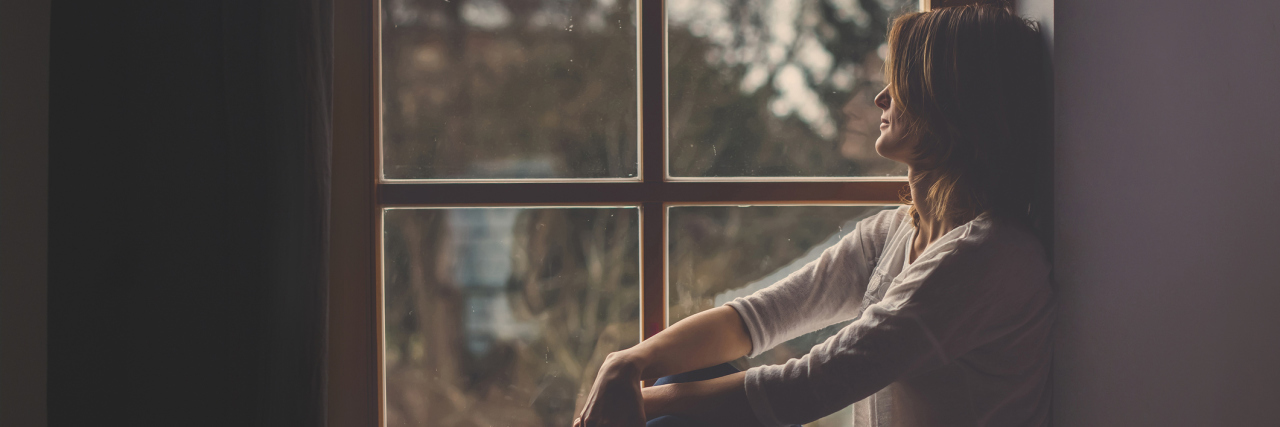 Having Unhealthy Relationships With Borderline Personality Disorder A woman sits alone, sadly looking out of a window.