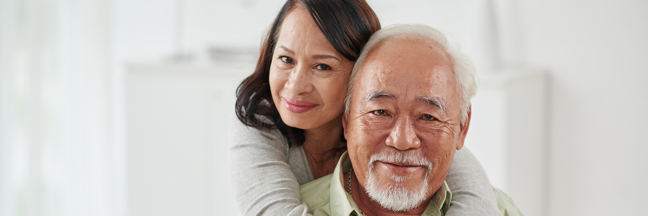 5 Ways to Maintain a Marriage When Your Partner Has a Chronic Illness Happy smiling aged woman hugging her husband from behind