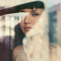 young woman looks at camera through a window