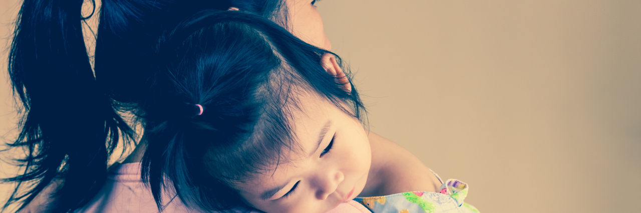 Parenting a Child With a Rare Disease and Dealing With Anxiety Mother carrying her daughter, who's wearing a hospital gown