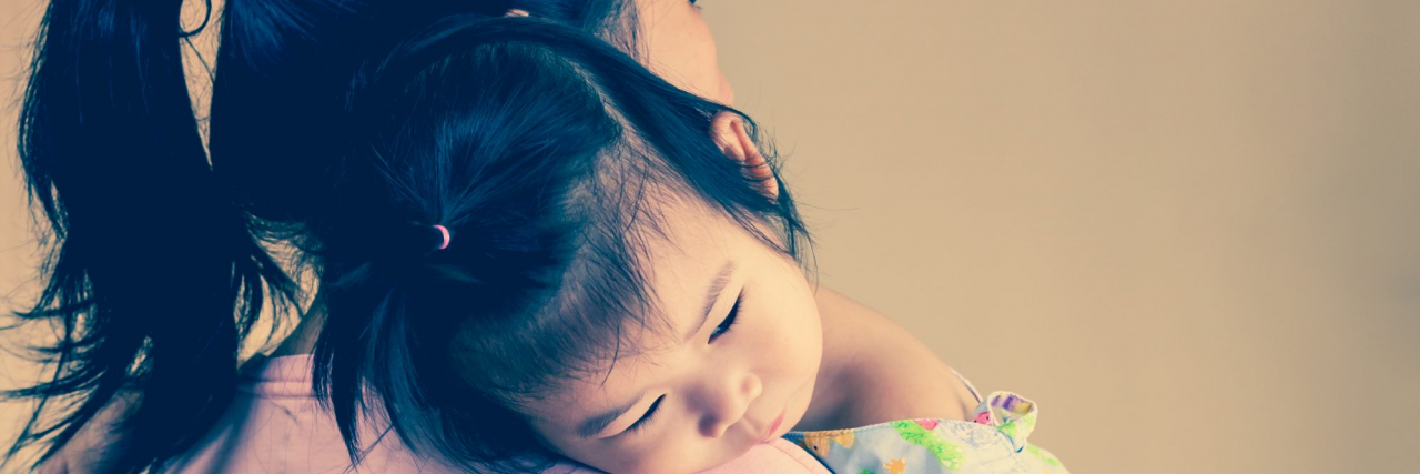 How I Learned to Celebrate My Daughter With Epilepsy for Who She Is Mother carrying her daughter, who's wearing a hospital gown