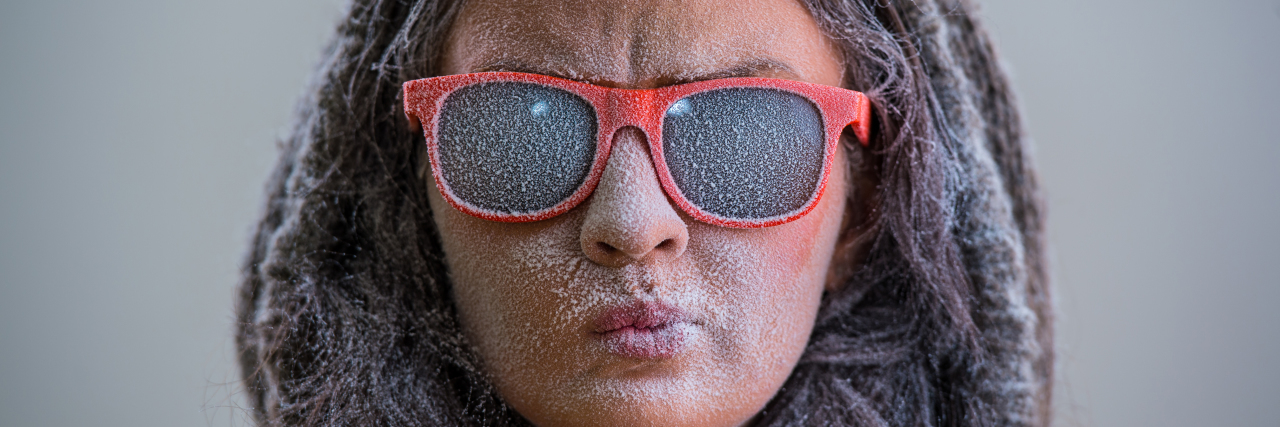 Woman with sunglasses and snow-covered face.