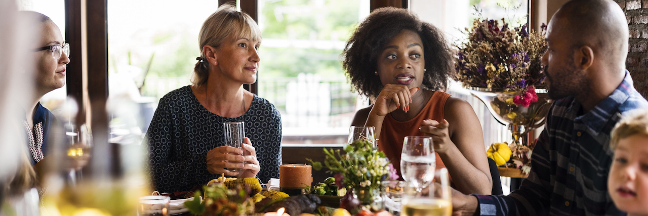 Diverse group of people sitting around a table having a meal during the holidays