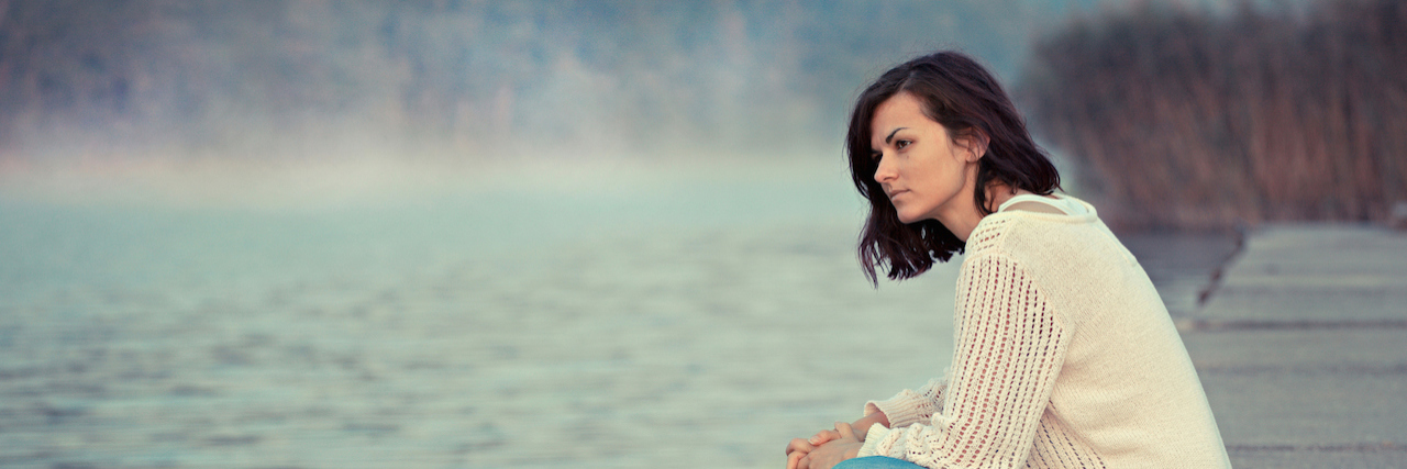 Living Your Best Life and Your Worst Life at the Same Time Young woman sitting by a lake