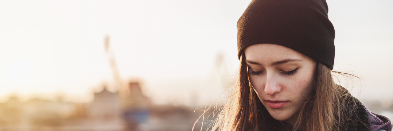 Up-dosing Your Cortisol Levels With Adrenal Disease A woman stands outdoors with a hat on.