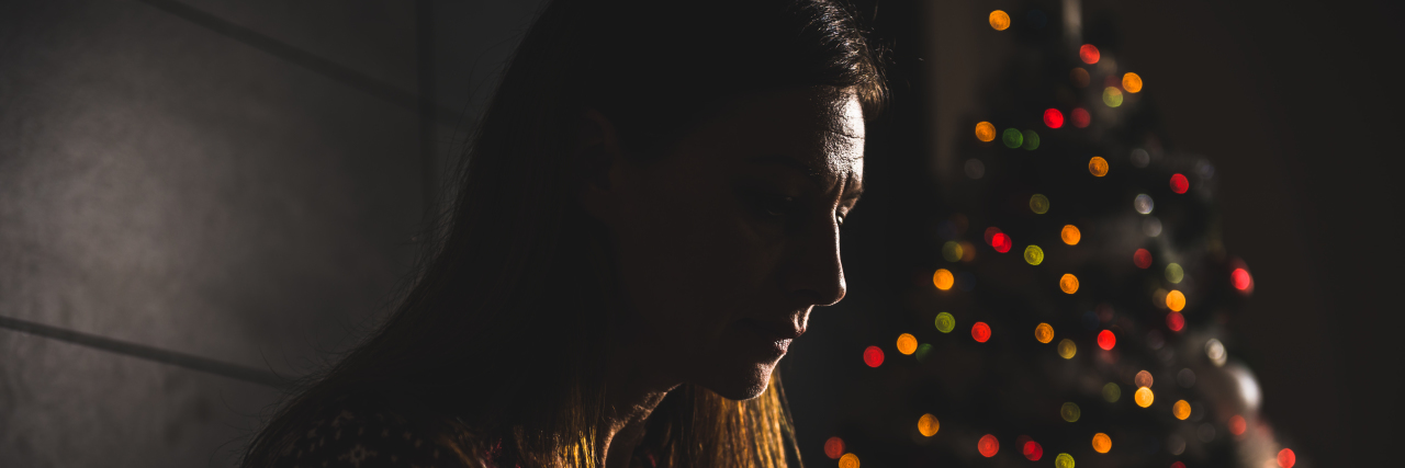 How to Cope With Grief During the Holiday Season a lonely woman sitting near a christmas tree