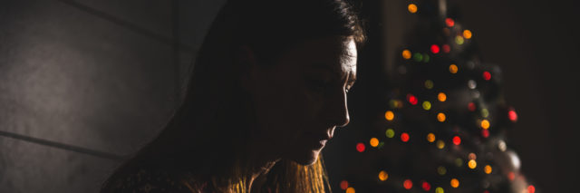 a lonely woman sitting near a christmas tree
