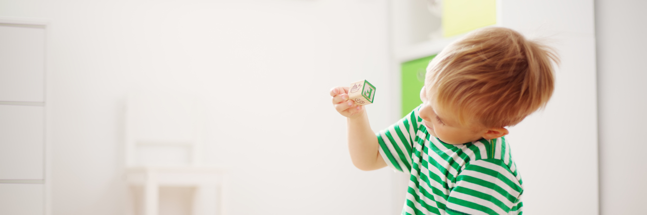 Learning to Speak as a Child With Autism Boy sitting on the floor playing with blocks.