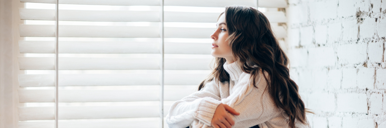 How to Cope During the Holidays With Mental Illness A young woman sits on a floor by Christmas decorations.