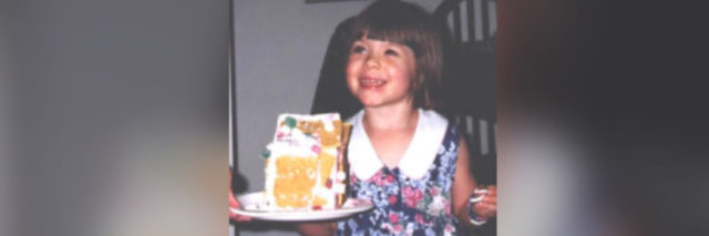 Photo of author as a child smiling in a dress holding a plate with a gingerbread house
