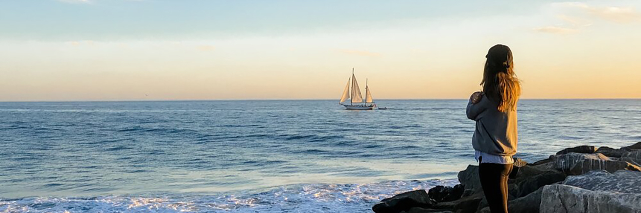 Understanding Neuro-Fatigue and the Exhaustion of Chronic Illness Natalie standing on rocks looking at the ocean.