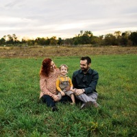 parents sitting with their son in a green field of grass