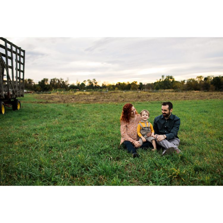 parents sitting with their son in a green field of grass