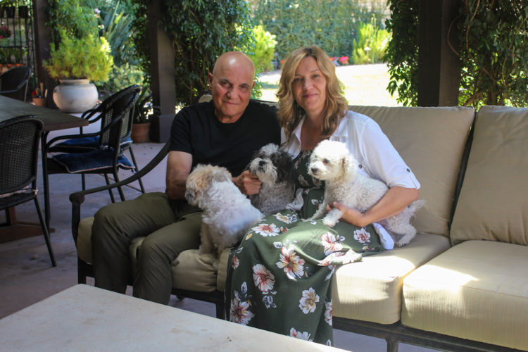 Tom and Dana Saputo sit in their backyard with their three dogs, Lindsey, Owen and Beatrice. (Anna Almendrala/Kaiser Health News)
