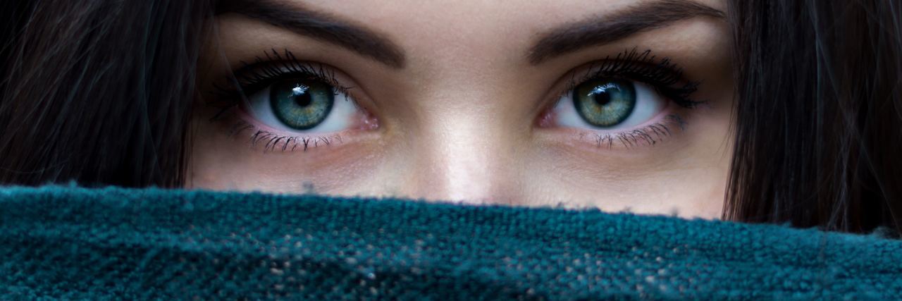 I Didn't Think Writing Could Help My Mental Health Until It Did photo of woman close up showing her eyes, dark hair and part of her face covered with blue cloth