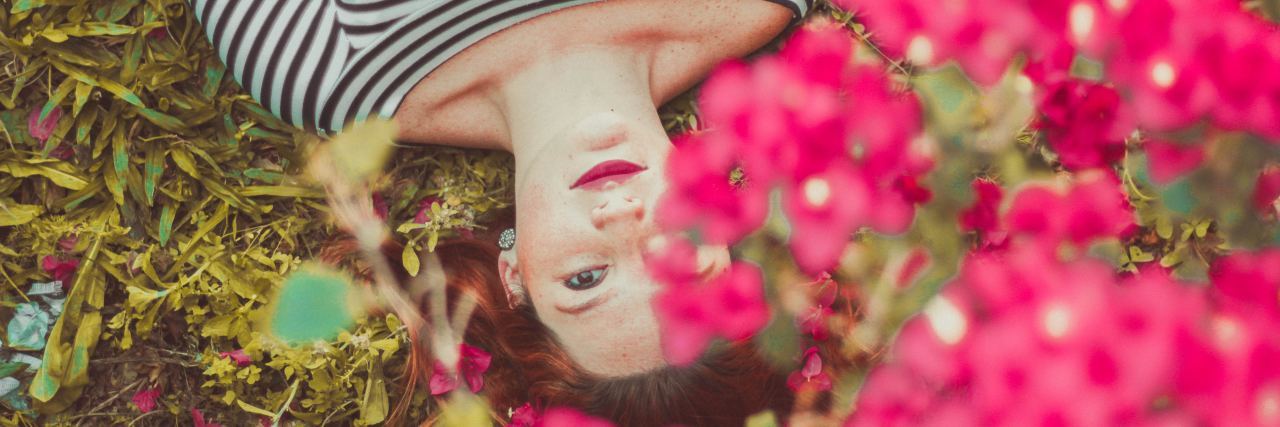 woman in a striped shirt lying down in a field of pink flowers
