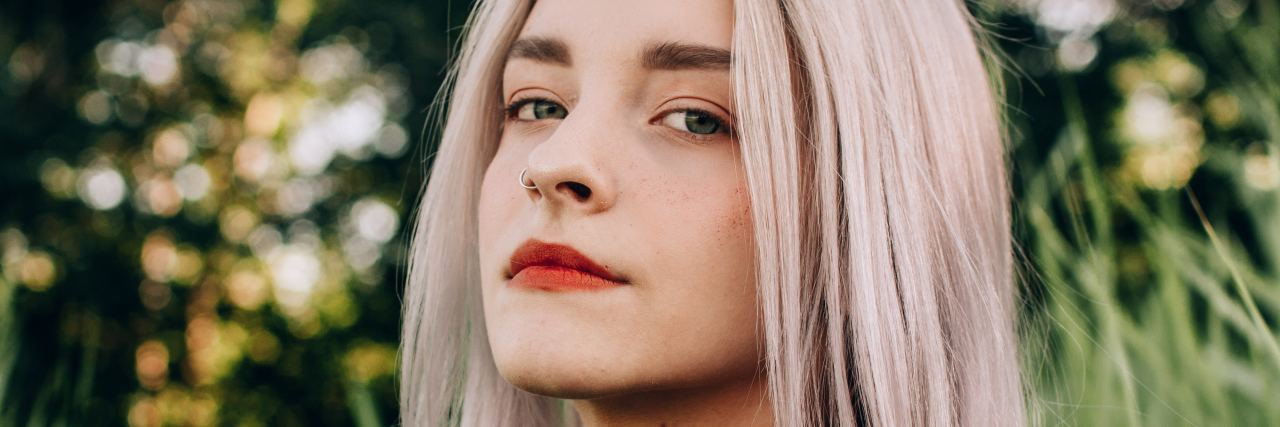 4 Things My Mental Illness Has Taught Me a woman with short blonde hair with purple streak looking to the camera with red lipstick on and a slight smirk on her face