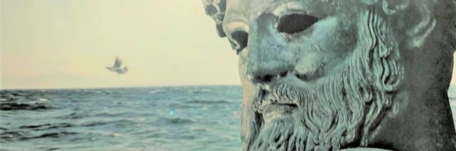 photo of a photograph showing a statue of poseidon beside the ocean, a light glare on his forehead