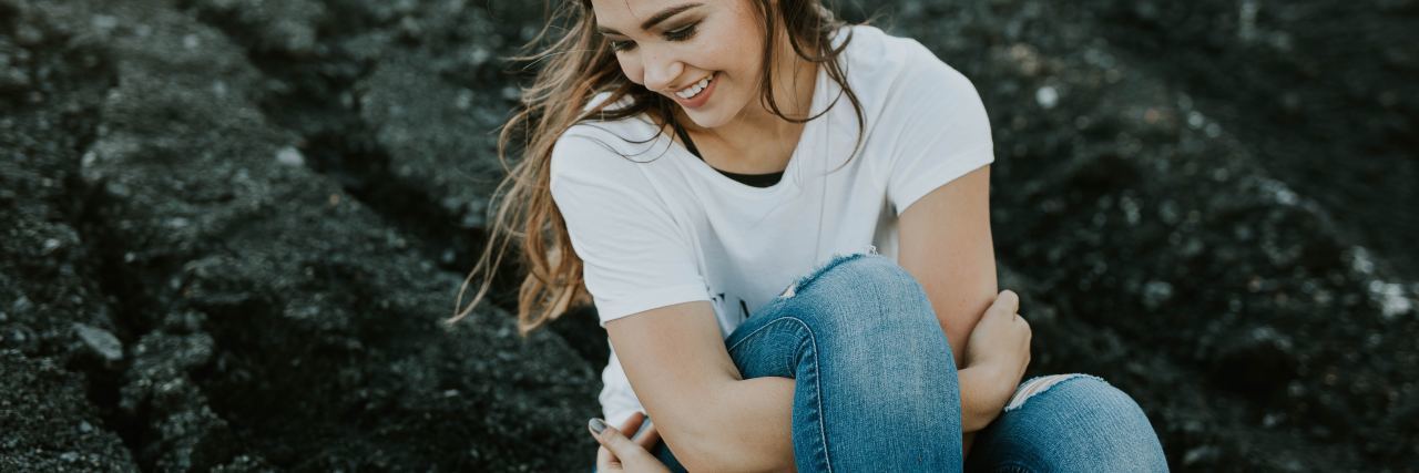 What to Expect From Pelvic Floor Physical Therapy photo of smiling woman with arms around one leg, looking away from camera