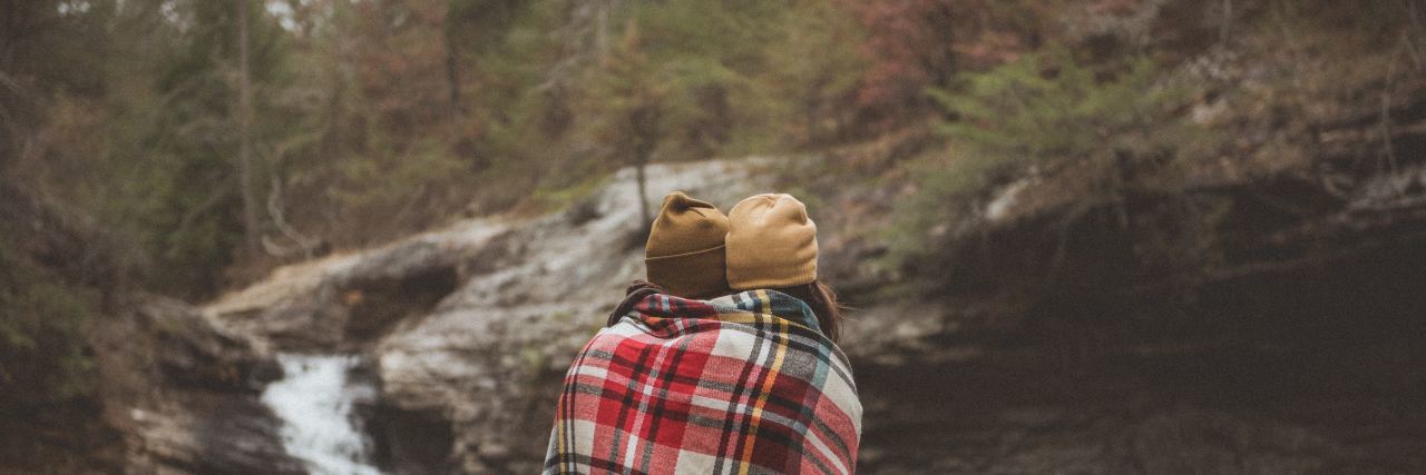 My Friend Redefined What Mental Strength Is Despite My Anxiety 2 girls wrapped in a blanket standing side by side with their backs to the camera in front of a lake