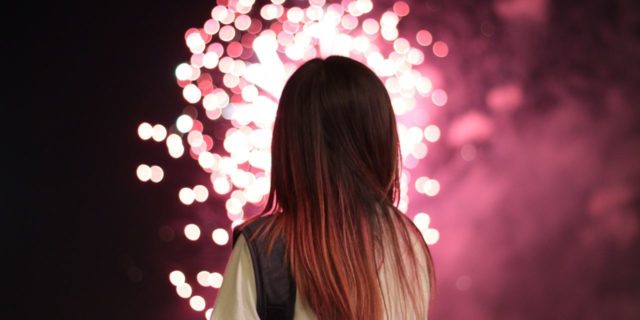 photo of woman silhouetted by fireworks