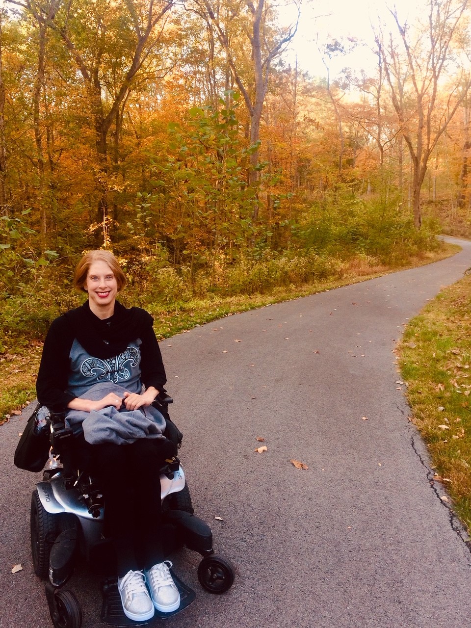 Jenny on an outdoor path with autumn trees.