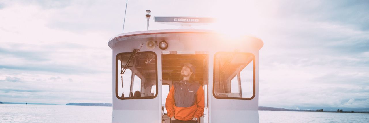 My Journey With Depression and the Metaphor That Helps Me Describe It photo of a man on a boat looking up, the sun behind him on a beautiful day