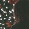 photo of woman standing in front of christmas tree out of focus